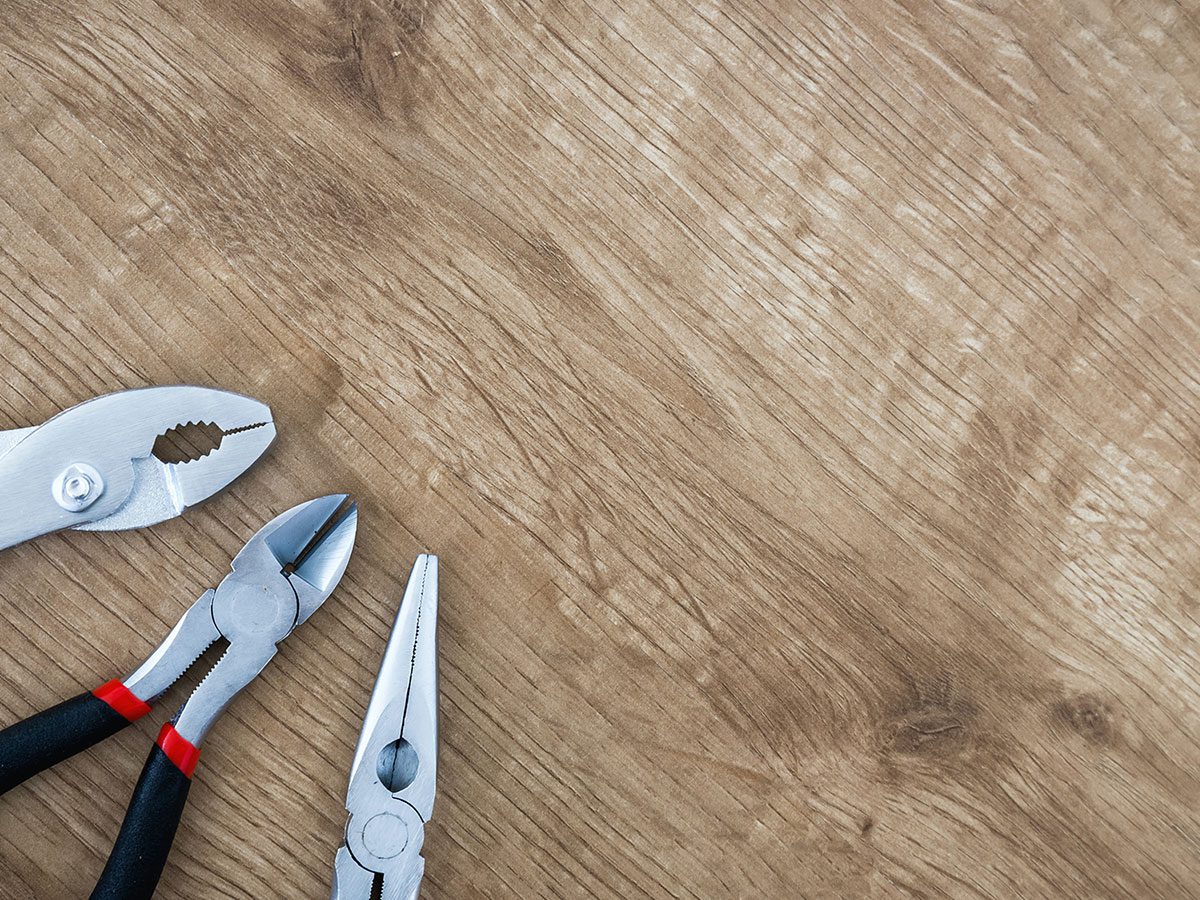 Three types of pliers sitting on a wooden surface
