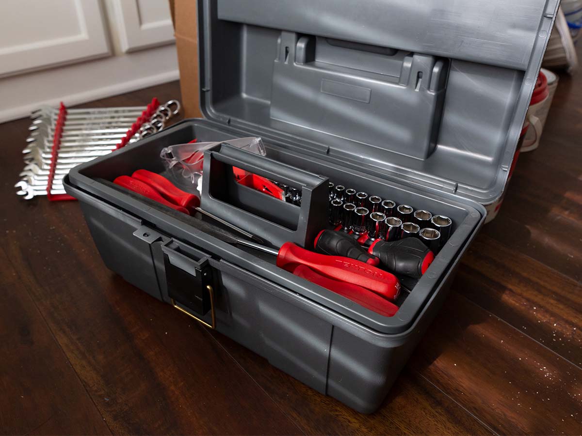 Open tool box with various red and black handled tools inside