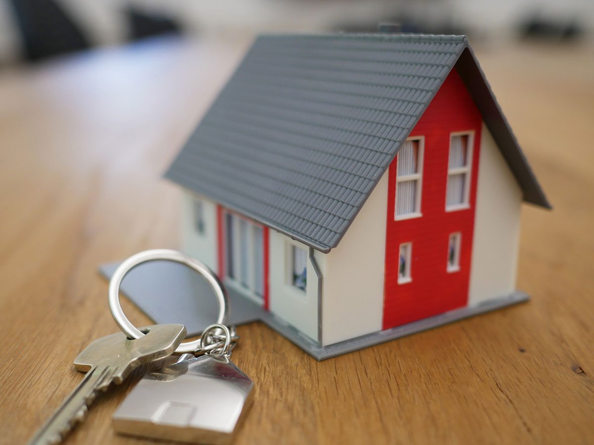 Small model house sitting next to keys on hardwood floors