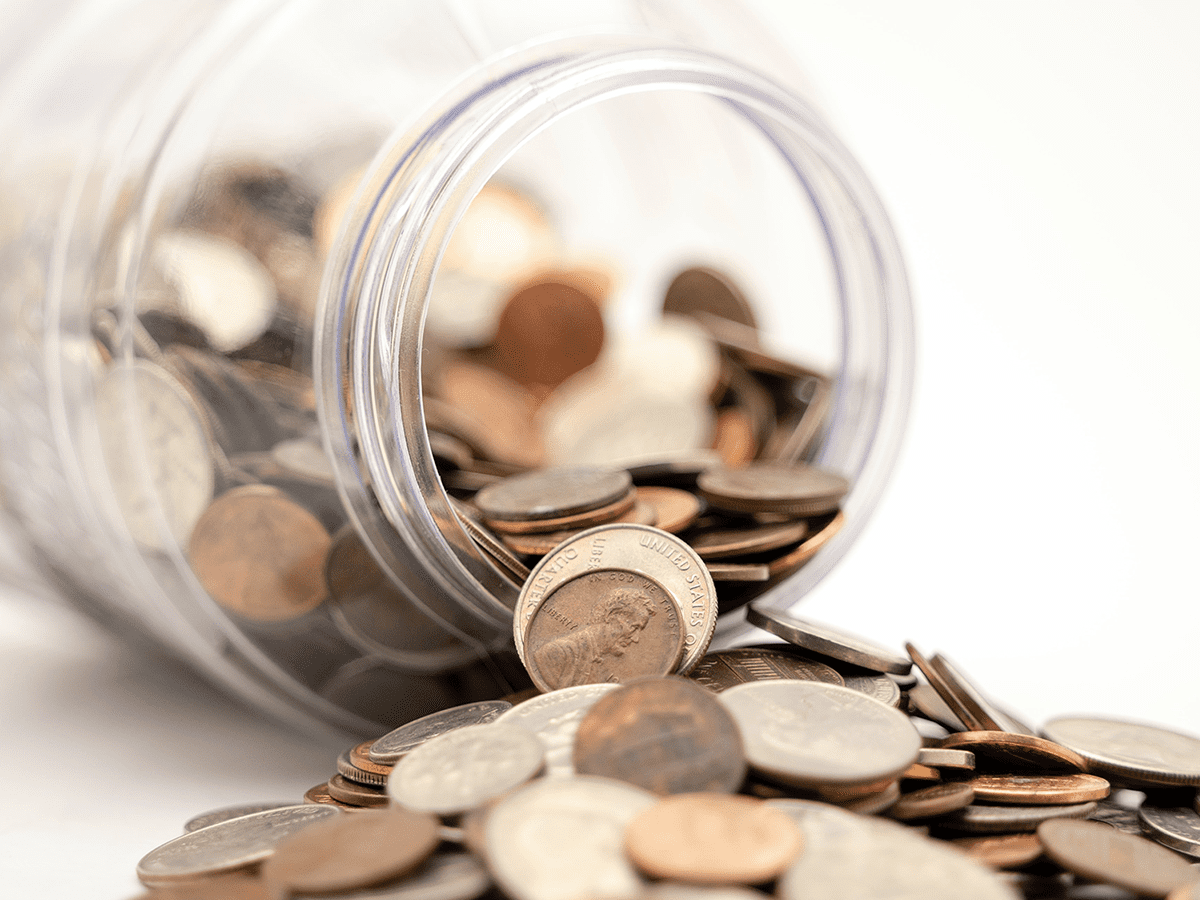 Person putting a dollar coin into a pink piggy bank