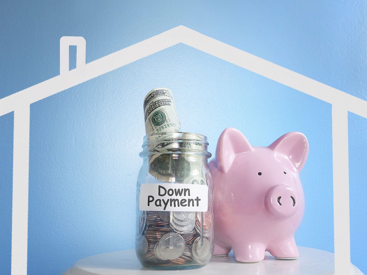 Piggy bank sitting next to a jar of money labeled Down Payment all inside an outline of a home