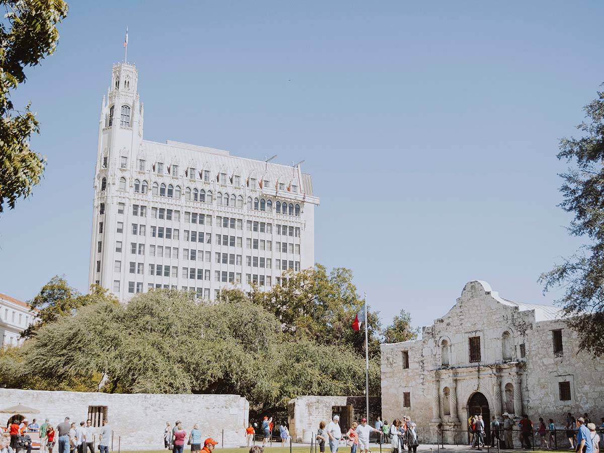 Person holding a set of keys with an apartment in the background.
