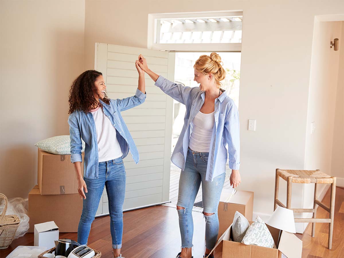 Person putting a dollar coin into a pink piggy bank