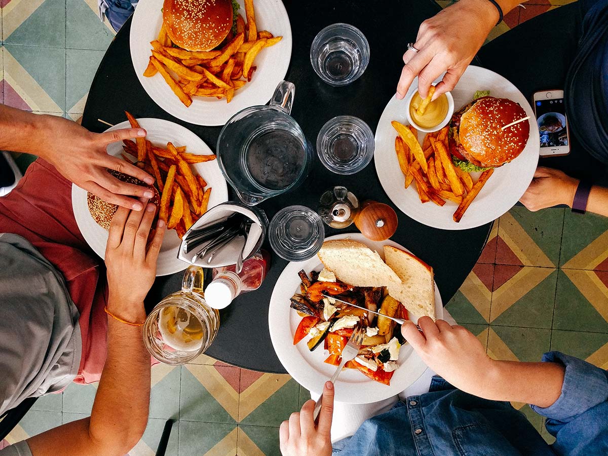Person putting a dollar coin into a pink piggy bank