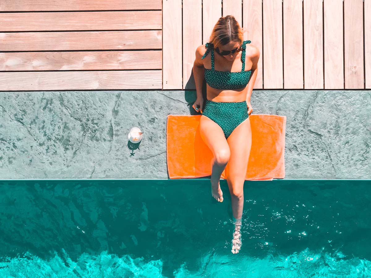 Person holding a wooden model of a home offering it to another person holding their hands out in front of them