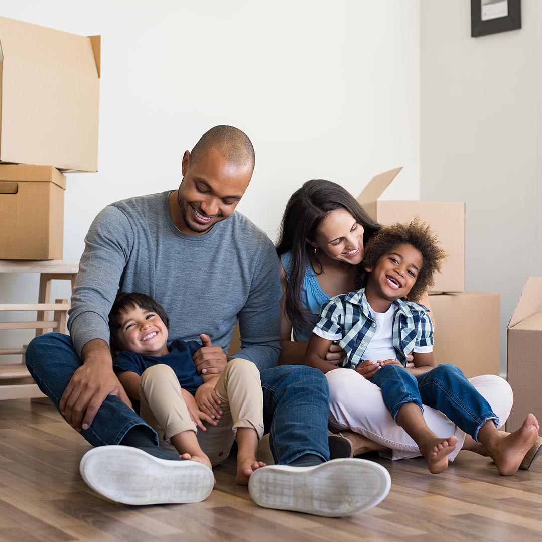 happy family sitting on the floor with boxes in the background
