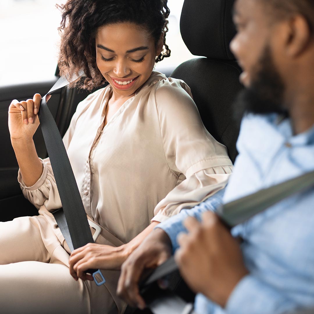happy couple putting on their seatbelts in their car