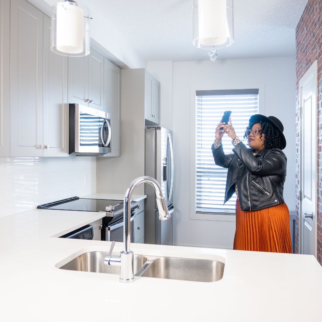 woman taking pictures of apartment kitchen