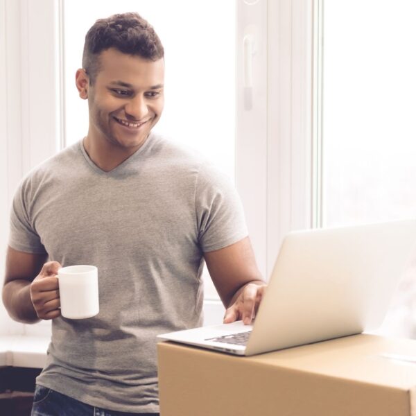 A man wokring on his laptop amid moving boxes.